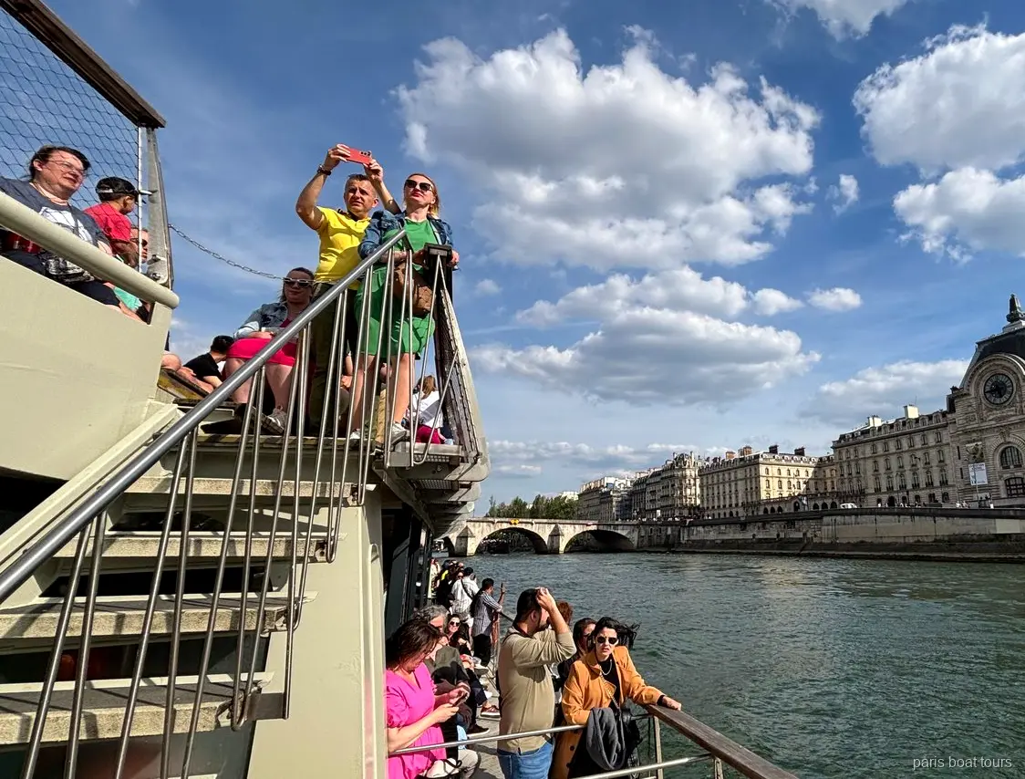 Passagers sur le pont supérieur avec le Musée d'Orsay sur la rive de la Seine, croisières à Paris