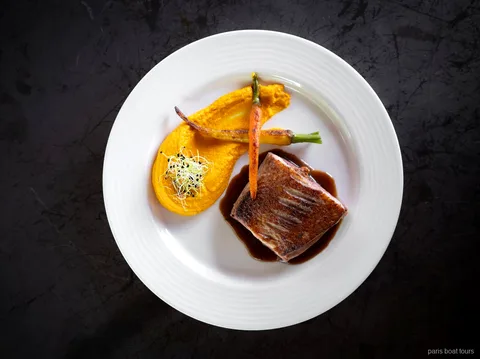 Main course of seared meat with carrot purée and baby carrots at a Bateaux Mouches dinner, one of the Paris boat tours