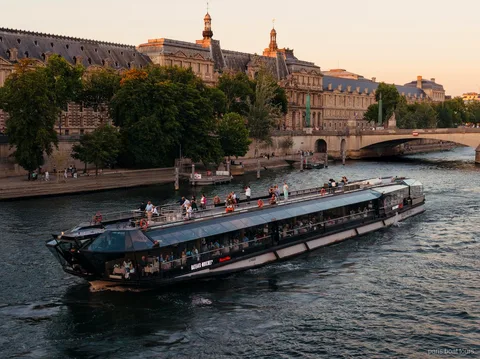 Bateaux Mouches Schiff gleitet in der Dämmerung an historischen Steingebäuden vorbei, Paris Bootstouren auf der Seine