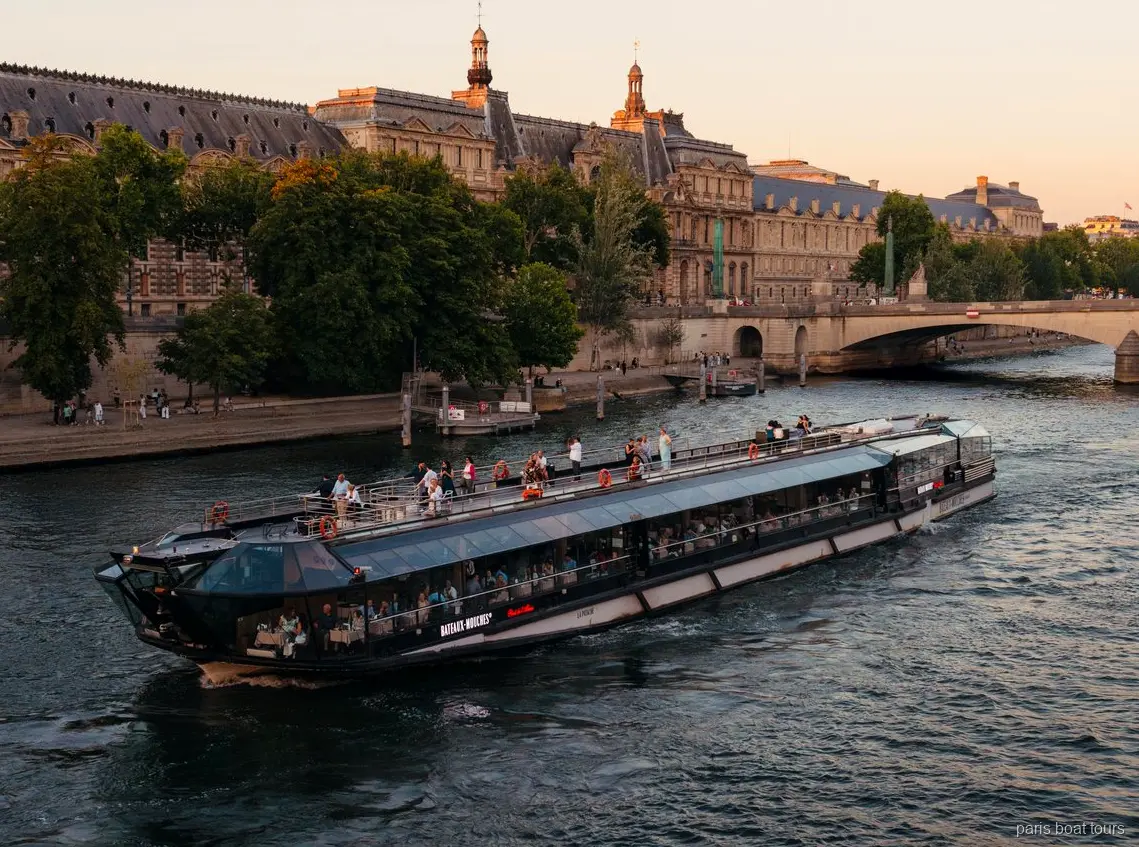 Statek Bateaux Mouches płynie Sekwaną o zmierzchu obok zabytkowych kamiennych budynków, rejsy po Paryżu
