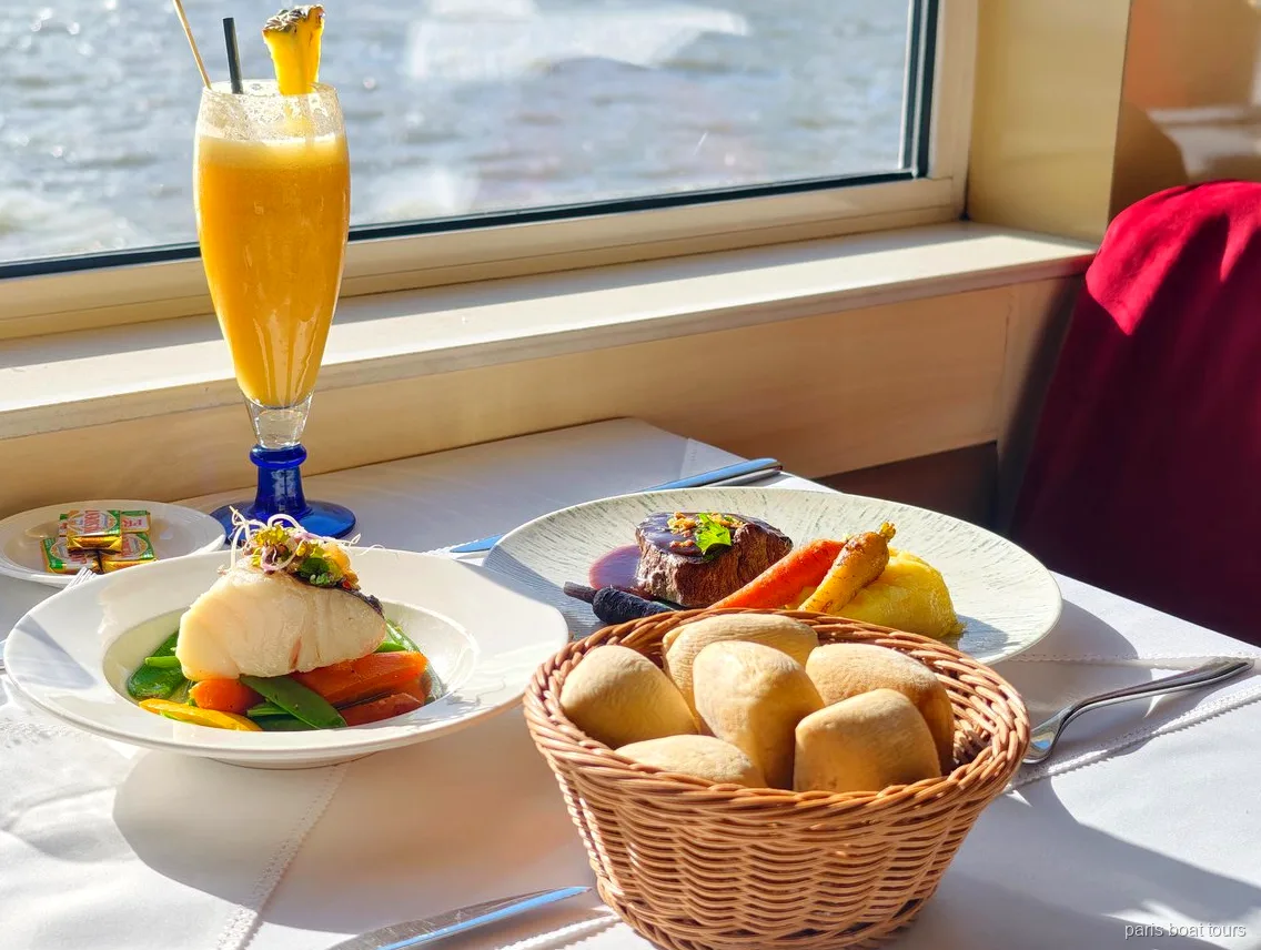Bord ved vinduet med fisk, oksekød, brødkurv og en frugtdrik, flodudsigt, sejlture i Paris