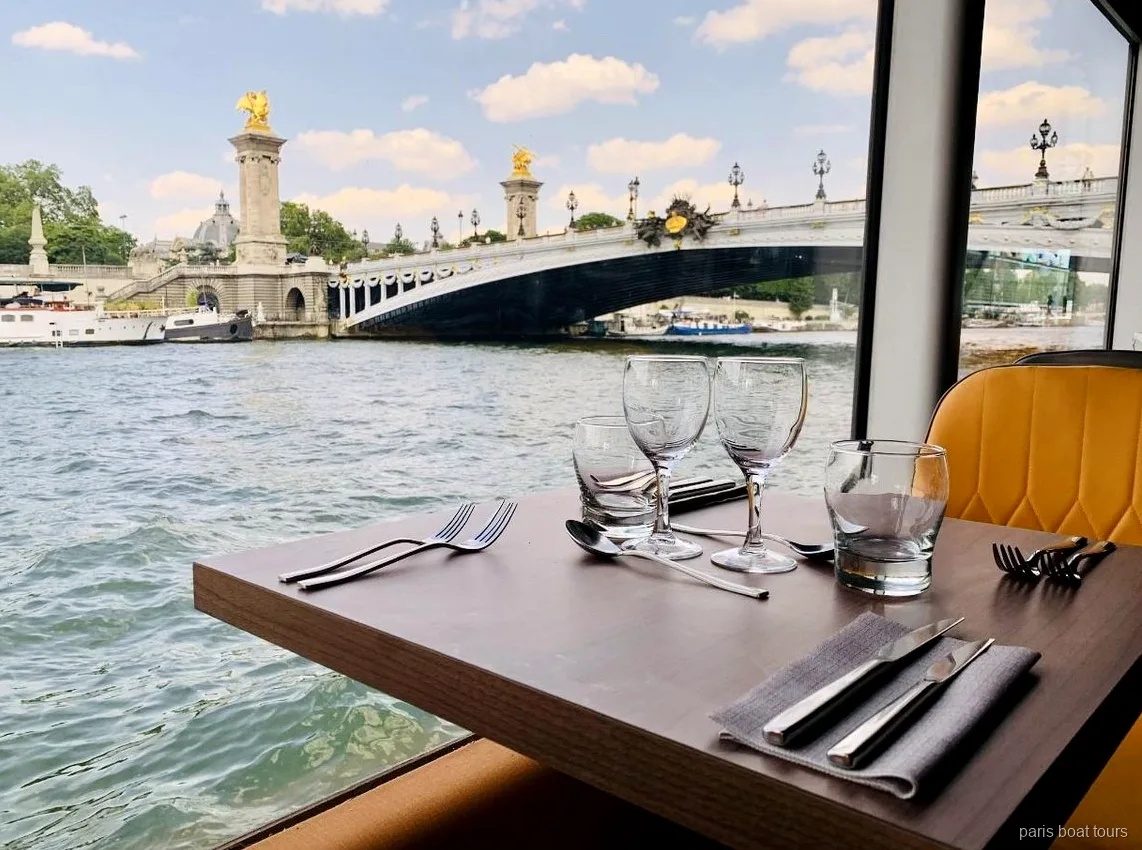 Dækket bord ved vinduet på en Paris boat tours sejlads med udsigt til Pont Alexandre III over Seinen