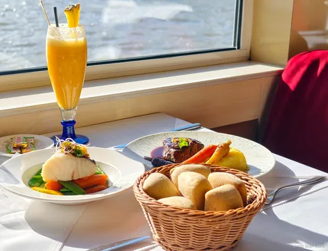 Bord vid fönstret med fisk, nötkött, brödkorg och fruktdryck, utsikt över floden, båtturer i Paris