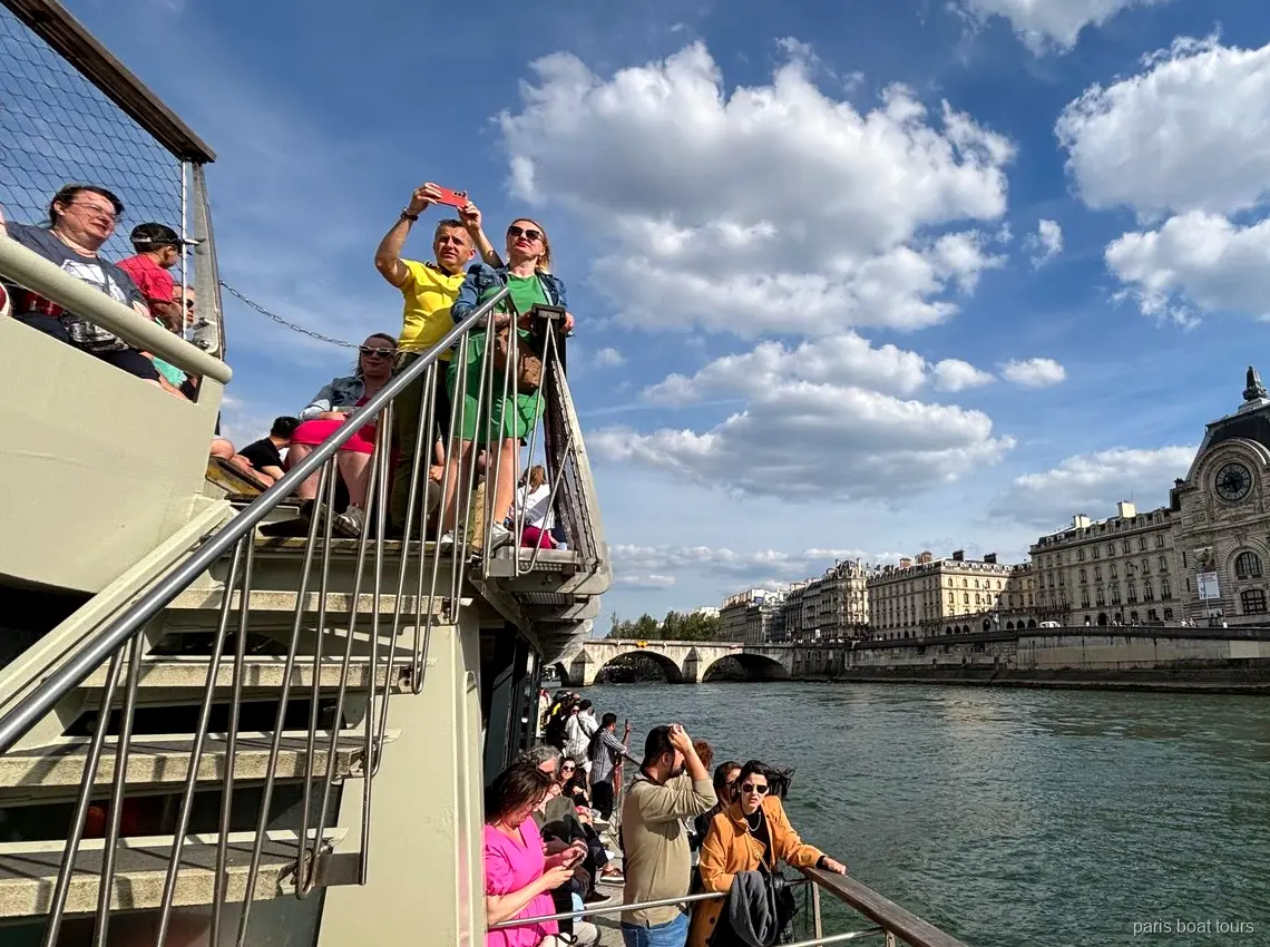 Passagiers op het bovendek met het Musée d'Orsay aan de oever van de Seine, boottochten in Parijs