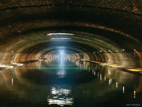 Gewelfde bakstenen tunnel met een lichtstraal boven het water op boottochten in Parijs