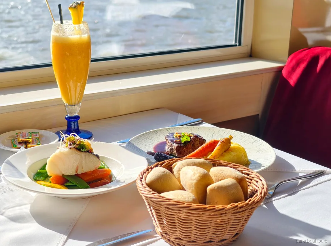 Tavolo vicino al finestrino con pesce, carne, cestino del pane e succo di frutta, vista sul fiume, tour in barca a Parigi
