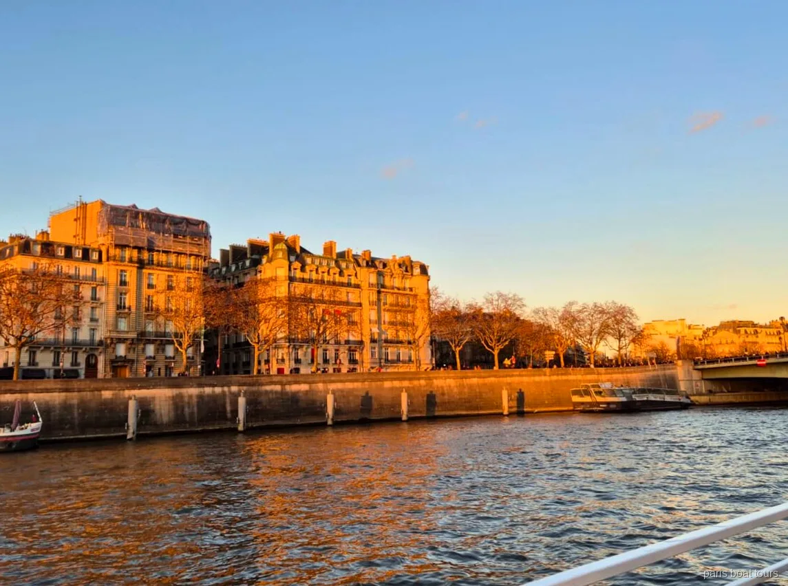 Haussmann-bygninger i gyldent aftenlys langs Seinens kaj set fra en sejltur i Paris