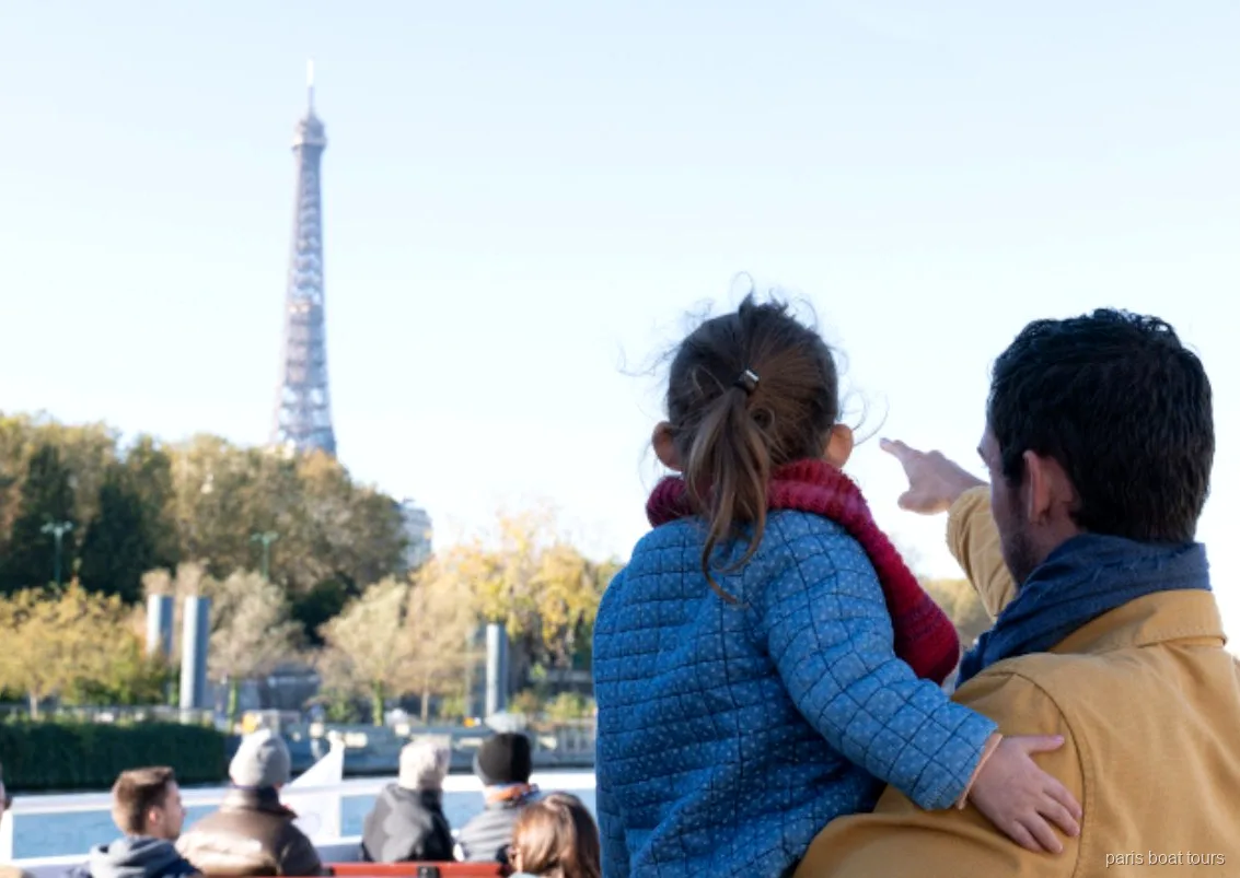 Paris tekne turlarından birinin güvertesinden Eyfel Kulesi'ni gösteren yetişkin ve çocuk