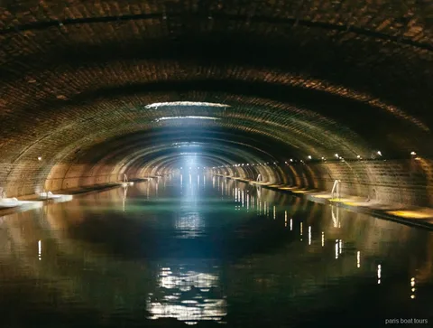 Túnel de maó amb volta i un raig de llum sobre l'aigua en passejades en vaixell per París