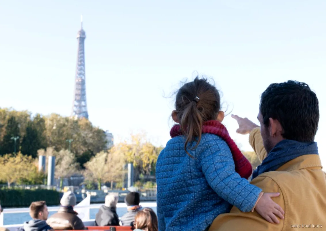 Adult i nen assenyalen la Torre Eiffel des de la coberta d'un dels creuers per París pel Sena