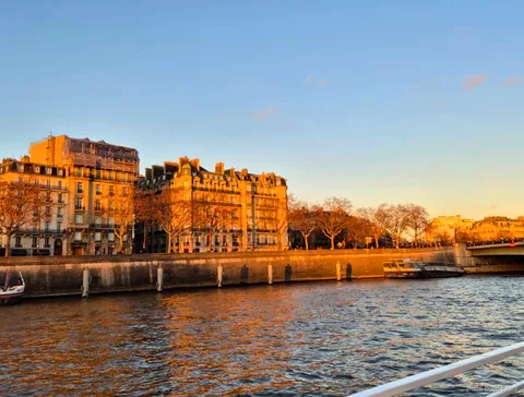 Edificis haussmannians il·luminats per la llum daurada del vespre al moll del Sena en un creuer per París
