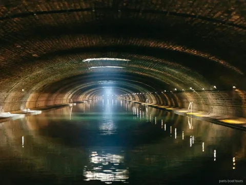 Tunnel a volta in mattoni con un raggio di luce sull'acqua nei giri in barca a Parigi