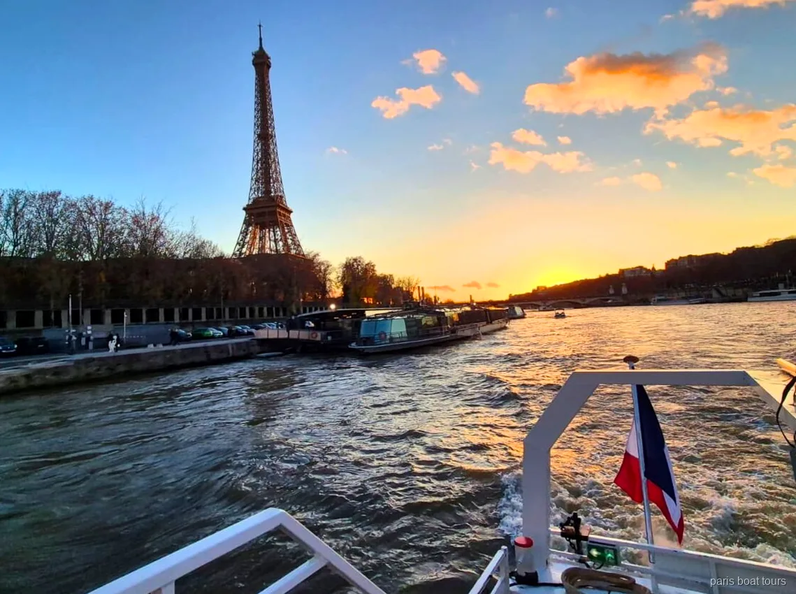 Torre Eiffel al tramonto vista dalla poppa di un tour in barca a Parigi con bandiera francese
