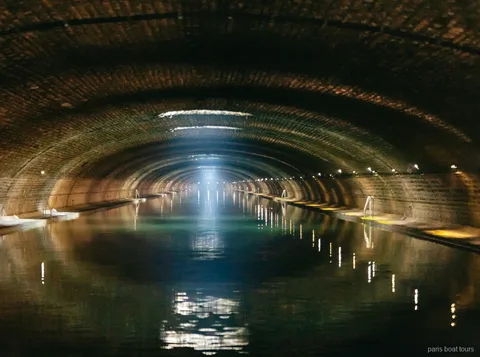 Tunnel voûté en brique avec un rayon de lumière sur l'eau pendant les croisières à Paris