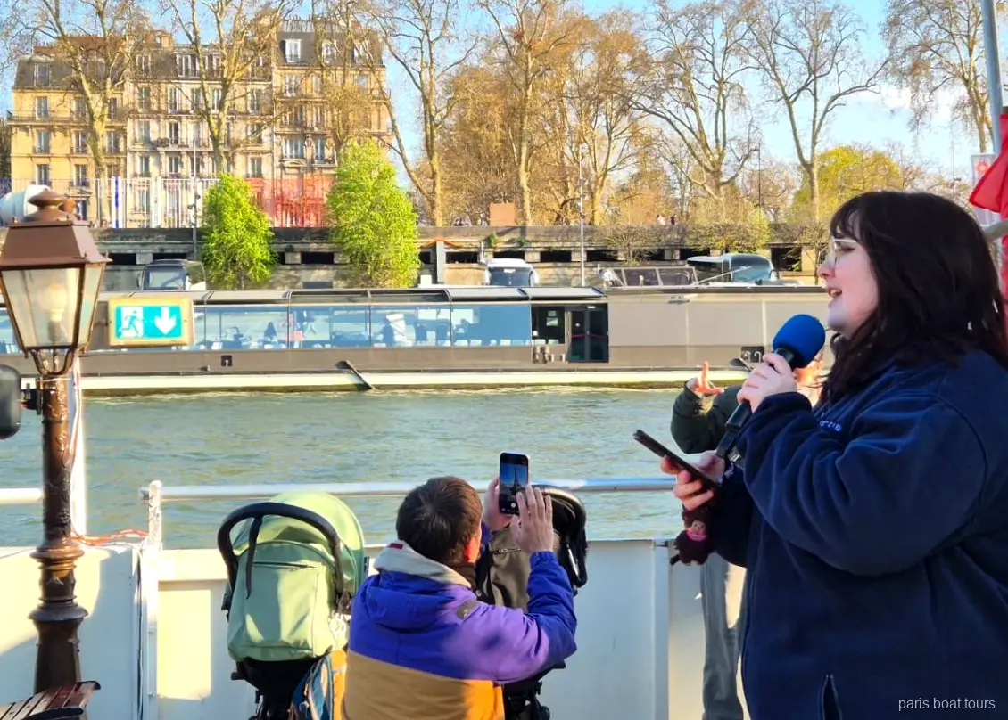 Guide au micro sur le pont pendant que des passagers filment le fleuve, croisières à Paris