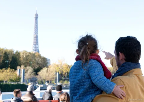 Adulte et enfant montrant la tour Eiffel depuis le pont d'une des croisières à Paris sur la Seine