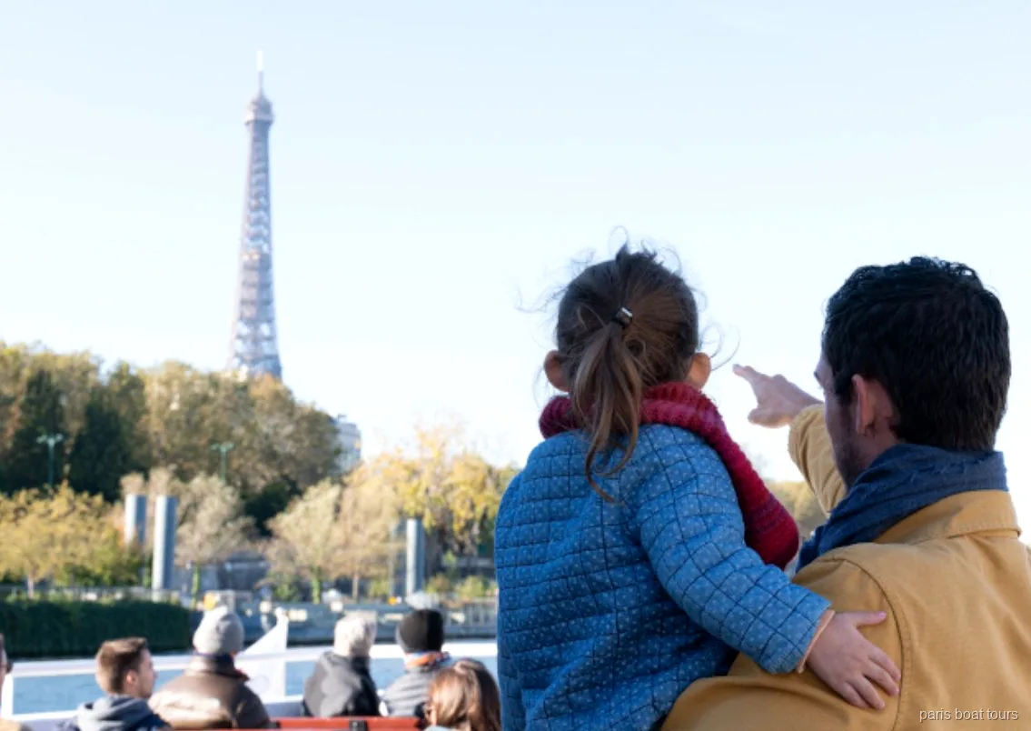 Adulte et enfant montrant la tour Eiffel depuis le pont d'une des croisières à Paris sur la Seine