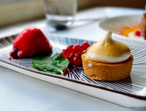 Plato de postre con una tartaleta de merengue, grosellas, menta y fruta roja, paseos en barco por París