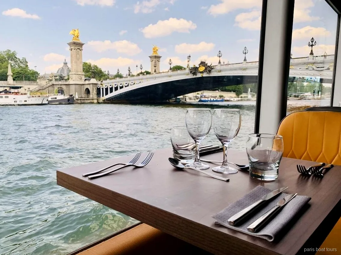 Mesa junto a la ventana en un paris boat tours con vistas al puente Alexandre III sobre el Sena