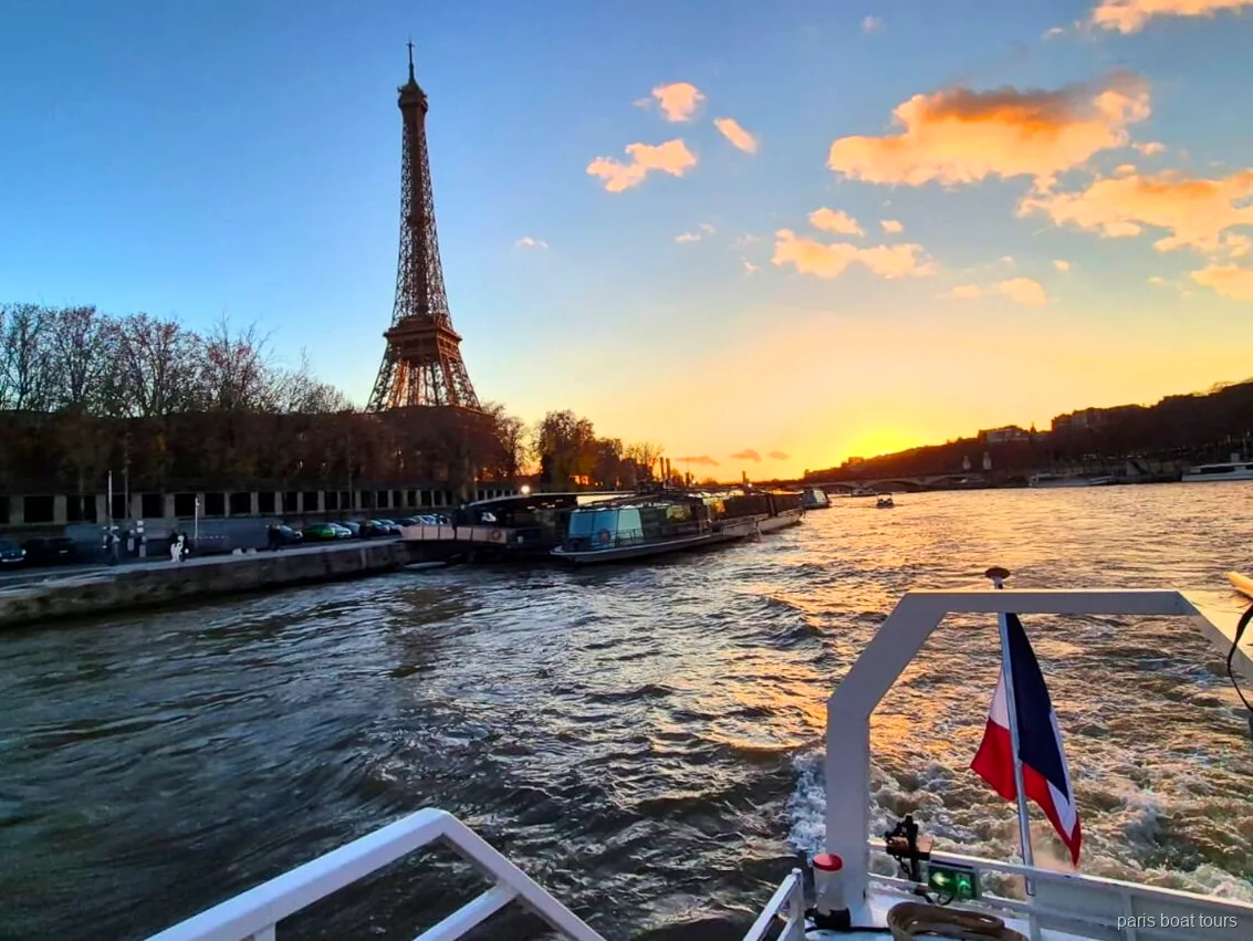 Torre Eiffel al atardecer vista desde la popa de un paseo en barco por París con bandera francesa