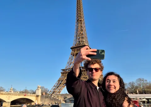 Pareja haciéndose un selfi con la Torre Eiffel detrás en uno de los paseos en barco por París