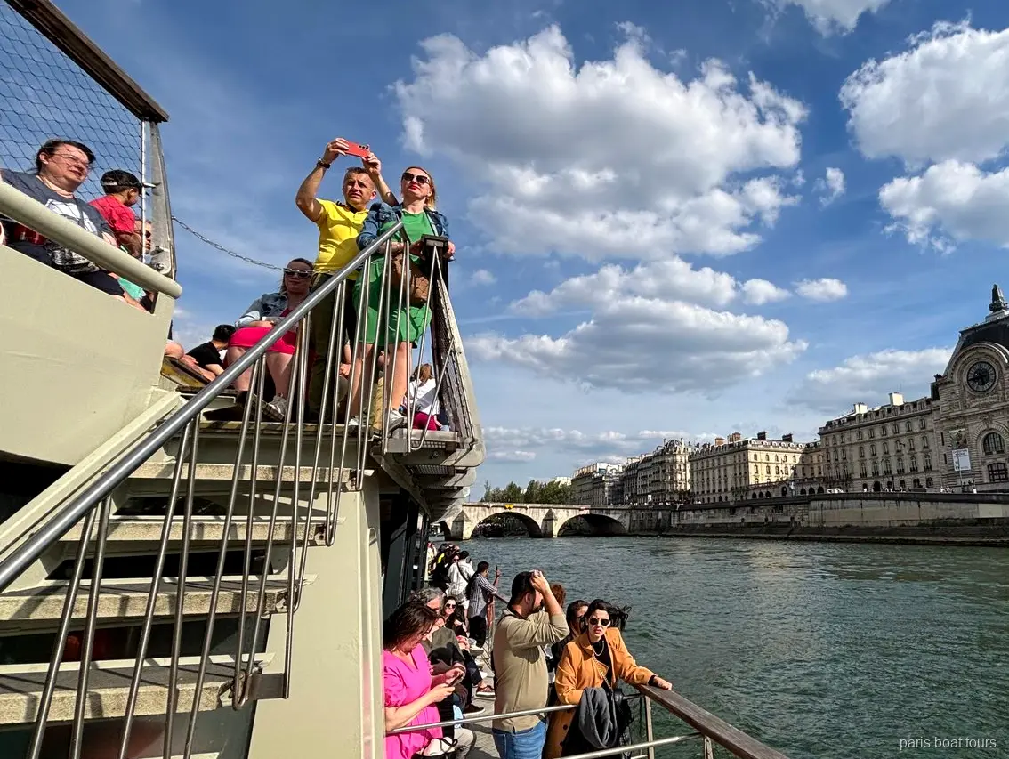 Pasajeros en la cubierta superior con el Musée d'Orsay en la orilla del Sena, paseos en barco por París