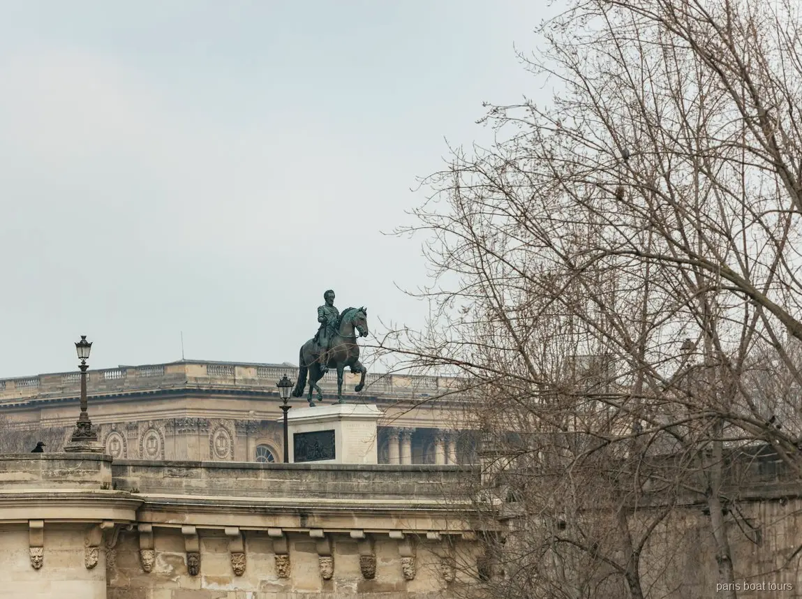 Estátua equestre de bronze numa ponte de pedra atrás de árvores nuas em passeios de barco em Paris