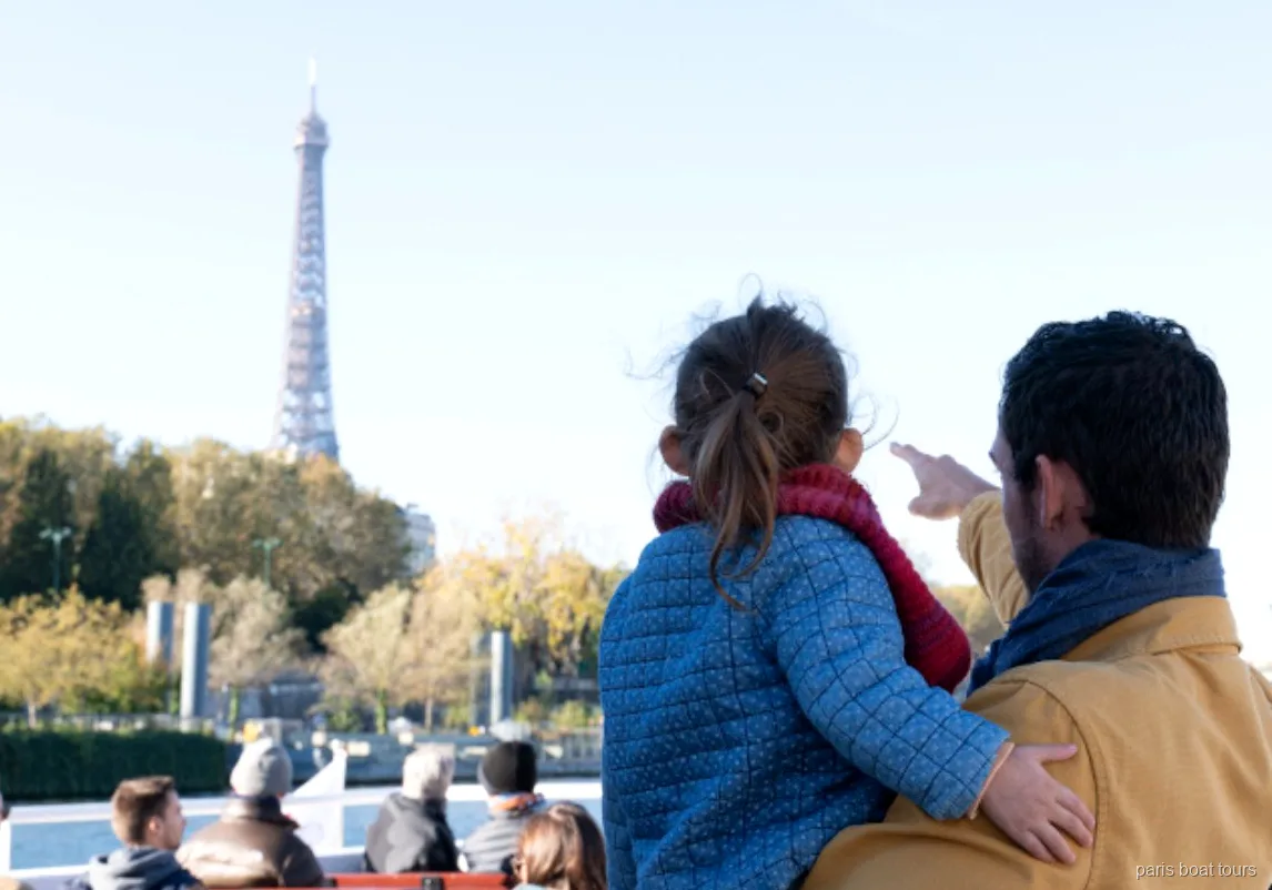 Adulto e criança apontam para a Torre Eiffel do convés de um dos passeios de barco em Paris