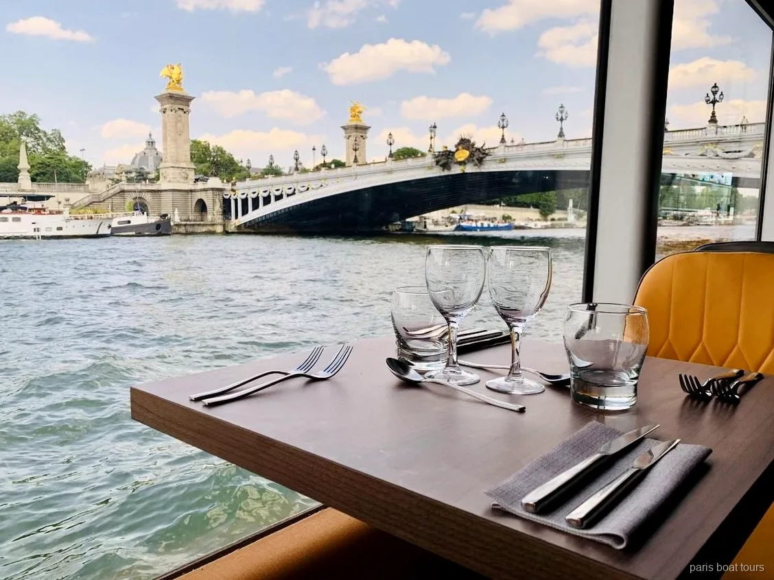 Mesa posta junto à janela num paris boat tours com vista da ponte Alexandre III sobre o Rio Sena