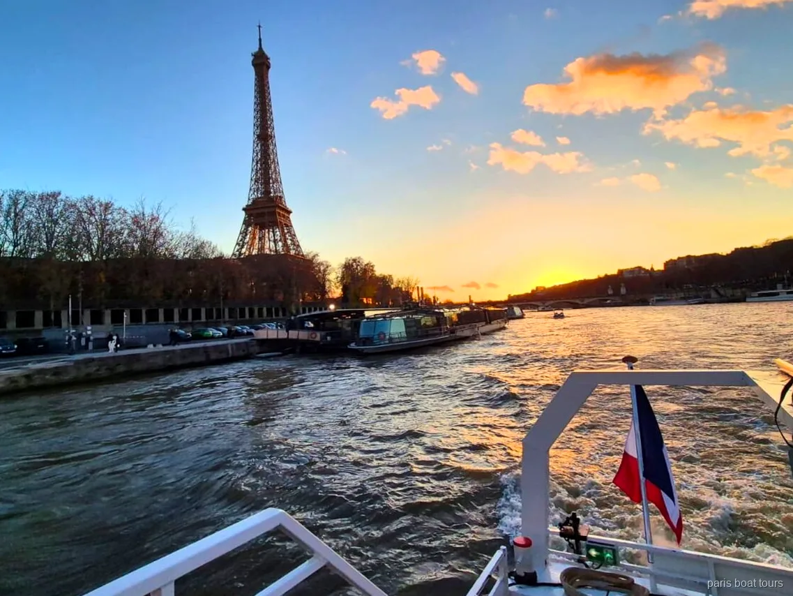 Torre Eiffel ao pôr do sol vista da popa de um passeio de barco em Paris com bandeira francesa