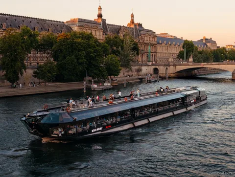 Bateau Bateaux Mouches naviguant sur la Seine au crépuscule devant des bâtiments historiques, croisières à Paris