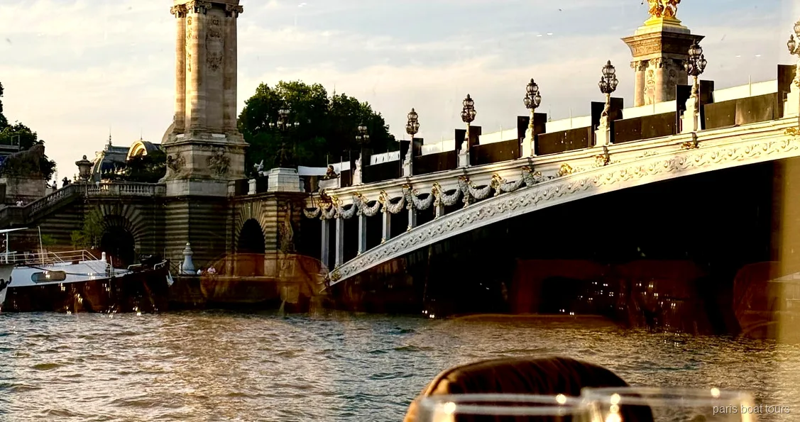 Bateau du dîner croisière bistronomique sur la Seine passant devant la tour Eiffel illuminée