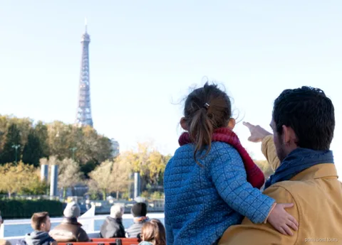 Voksen og barn peger på Eiffeltårnet fra dækket på en af Paris' sejlture på Seinen