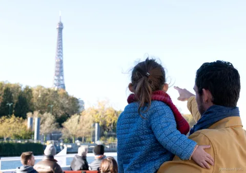Vuxen och barn pekar på Eiffeltornet från däcket på en av båtturerna i Paris