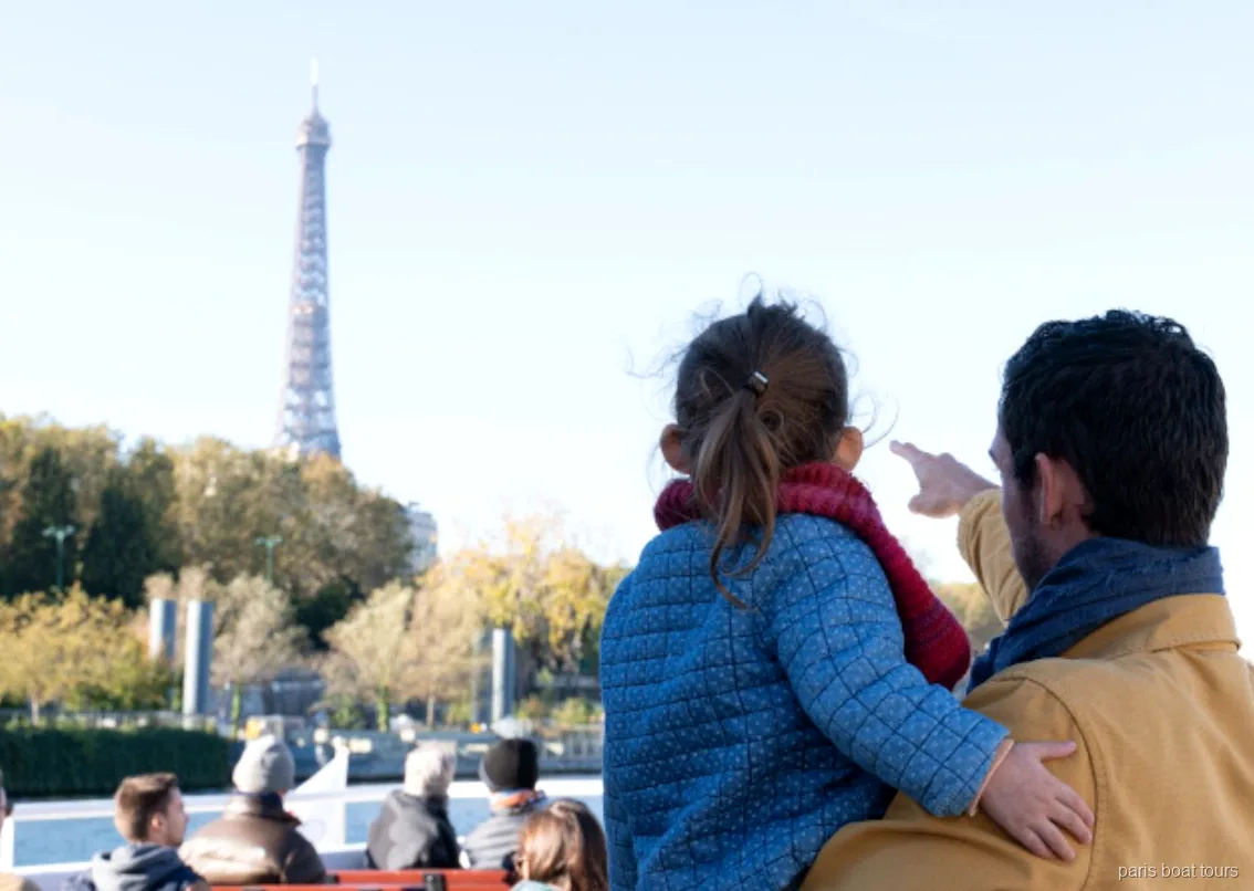 Adult and child pointing at the Eiffel Tower from the deck of one of the Paris boat tours