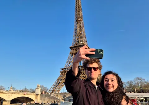 Couple taking a selfie with the Eiffel Tower behind them on one of the Paris boat tours