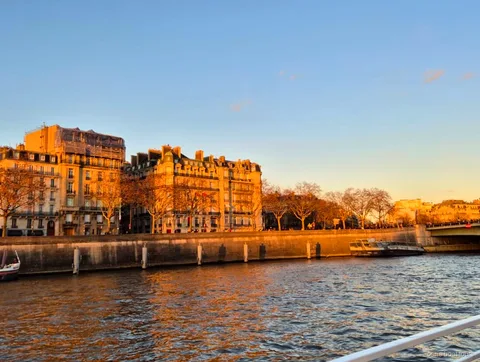 Haussmann buildings glowing in golden evening light along the Seine quay, seen on Paris boat tours