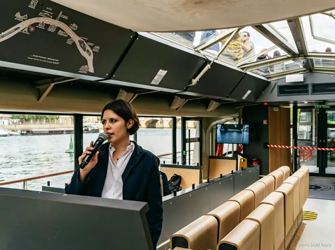Guide med mikrofon i en båd med glastag ved siden af et rutekort, bådture i Paris