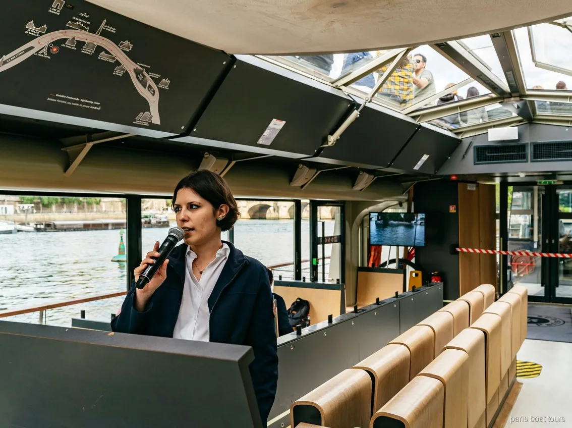 Guide med mikrofon i en båd med glastag ved siden af et rutekort, bådture i Paris