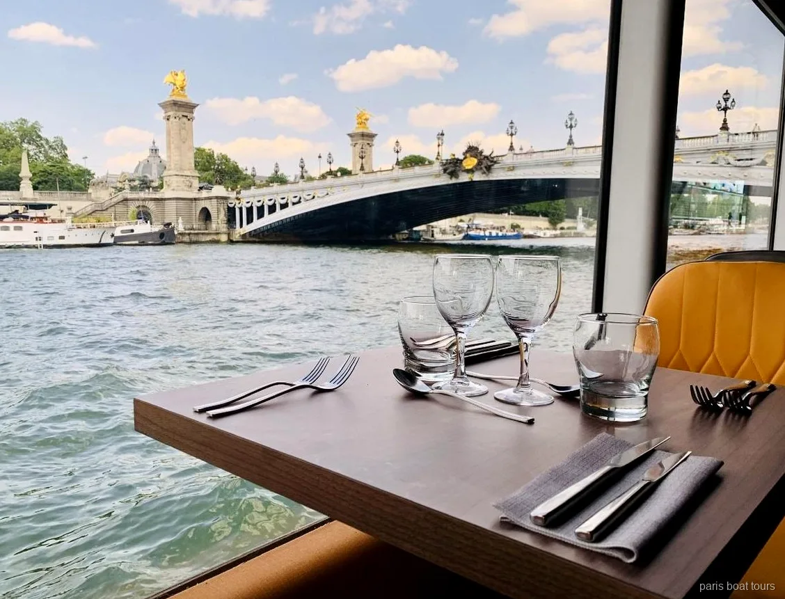 Taula parada vora la finestra en un dels paris boat tours amb vista al pont Alexandre III sobre el Sena